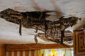cracked ceiling, sagging roof inside old abandoned house in the country. hole in ceiling. ruin.