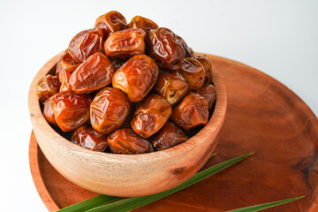 Dates fruit sukari or kurma sukari, in wooden bowl isolated on white background