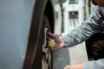 Checking tire pressure at a gas station for vehicle safety and performance during a sunny afternoon