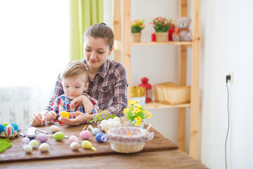 A woman and her child are happily decorating Easter eggs together