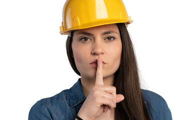 Female construction worker with yellow hard hat, gesturing for silence