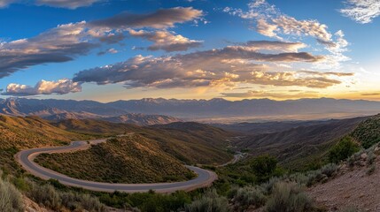 A winding road leads through mountains under colorful evening clouds