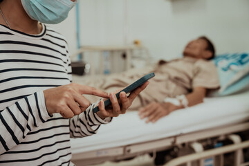 A daughter sits by her elderly father's hospital bedside, caring for him, giving him medicine, holding his hand and encouraging him as he struggles with the stress of his treatment and medical bills