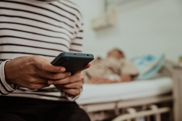A daughter sits by her elderly father's hospital bedside, caring for him, giving him medicine, holding his hand and encouraging him as he struggles with the stress of his treatment and medical bills