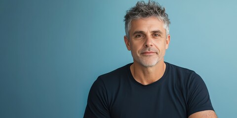 Obraz premium Confident Middle-Aged Man with Stylish Hair Against a Blue Background