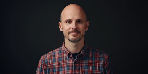 Obraz premium Portrait of a Confident Man in a Plaid Shirt Against a Dark Background