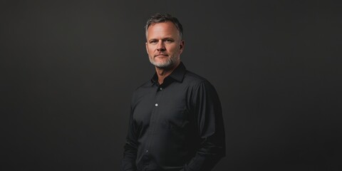 Obraz premium Confident Middle-Aged Man in Black Shirt Posing Against Dark Background
