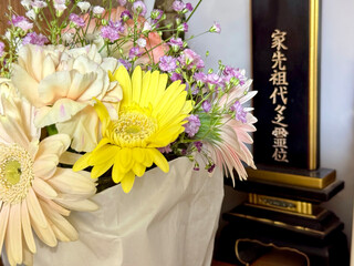 位牌の前に黄色い花などたくさんの供花