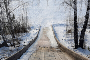 Steep descent from the wooden hill from top to bottom. The snow hill has melted. Slide for sledding and tubing.