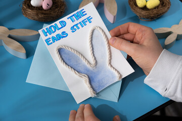 Person holding handmade greeting card with message HOLD THE EARS STIFF written in beautiful...