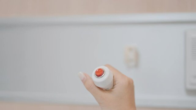 Elderly woman Patient hand holding and pressing emergency button in hospital room, calling nurse in emergency case. Professional Medical system and Safety Alert