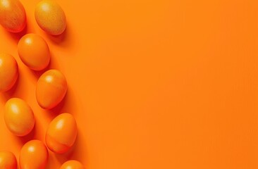 Festive Easter background with colorful eggs arranged on the left side on a bright orange background in flat layout.