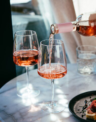 Pouring rose wine at a dinner party with friends in a bar or restaurant.