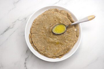 Jowar flour flatbread known as bhakar or jawari bhakri. served with ghee, spicy garlic or lasun chutney, bhindi or lady finger sabji. farmer's food. Maharashtrian village food. copy space.