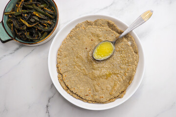 Jowar flour flatbread known as bhakar or jawari bhakri. served with ghee, spicy garlic or lasun chutney, bhindi or lady finger sabji. farmer's food. Maharashtrian village food. copy space.