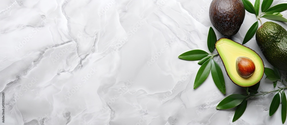 Poster fresh sliced avocado with a glossy green peel placed left on a light marble background with whole av