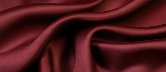 Obraz premium Rich burgundy silk fabric draped elegantly with smooth, flowing creases and a lustrous sheen showcasing luxury and sophistication.