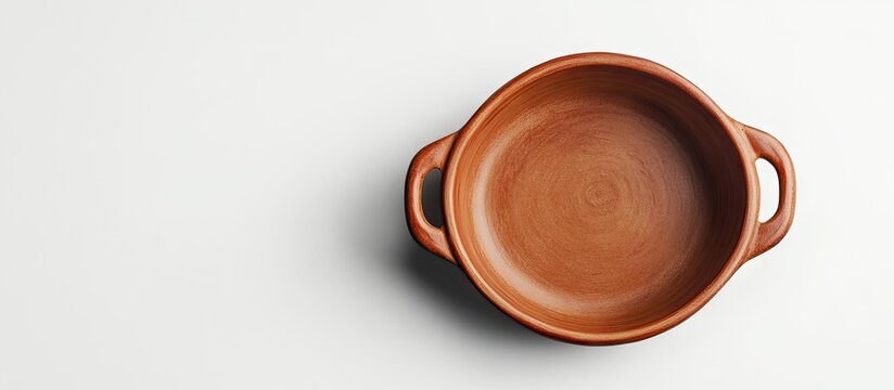 Round clay baking pan viewed from above, terracotta color, positioned centrally on a bright white background, featuring two side handles.
