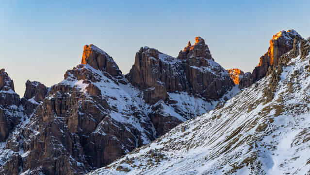 the illuminated peaks of snow-capped mountains in Italy. Dolomites in winter at sunset. Italian mountains under snow lit by the sun. Rocky mountains. Winter in the Dolomites