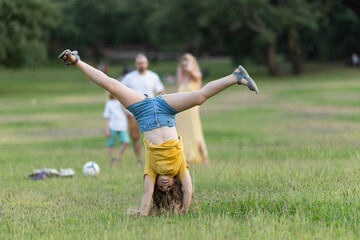Young girl doing a cartwheel in the park while family watches
