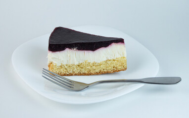 A slice of cheesecake with a vibrant berry topping sits on a white plate