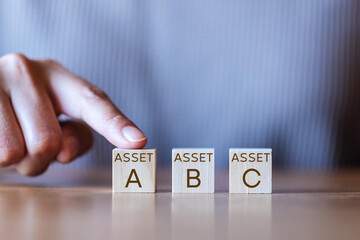 Investment asset allocation, Real estate investment. Money wealth management with funds. Diversification and risk management. Hand choosing on stacking coins with Assert A B C words on wooden blocks