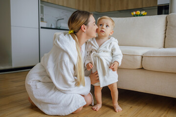 Mother and toddler bonding together wearing cozy matching bathrobes at home