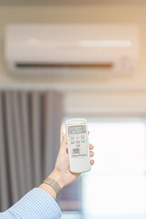 operating and adjusting Air conditioner temperature by remote control in home. Hand holding remote control and setting comfortable temperature on climate system in office or apartment. hot and cool