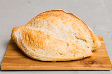 Freshly baked bread on cutting board against white wooden background. perspective view bread with copy space