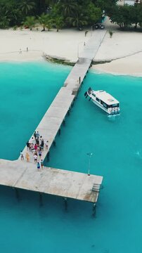Aerial shot of the Maldives Fulidhoo inhabited island with sapphire waters and white speedboats picking up tourists at the T-shaped pier