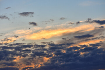 Dark clouds and orange clouds in the blue evening sky at sunset