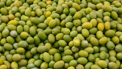 Background of green olives with smooth shiny surfaces natural shades of yellow and light green...