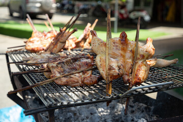 A few pieces of chicken are being cooked on a grill