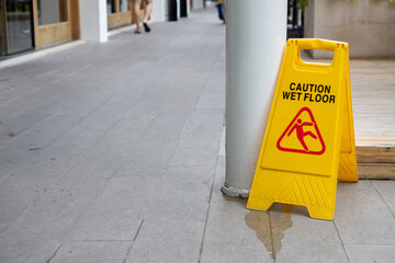 A yellow caution sign is on the ground in front of a building