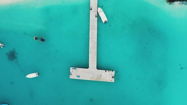 Aerial shot of the Maldives Fulidhoo inhabited island with sapphire waters and white speedboats picking up tourists at the T-shaped pier