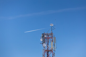 A towering telecommunications antenna with multiple antennas and dishes set against a clear blue sky. Modern technology and communication infrastructure. 5g gsm antenna