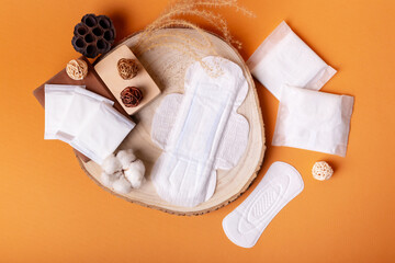 Menstrual hygiene pads from above on a wooden desk on orange background. Soft cotton absorbent...