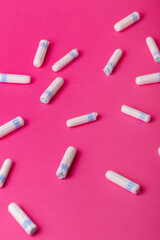 Many menstrual hygiene tampons from above on pink background. Soft cotton absorbent menstrual tampons for women during menstruation. Feminine hygiene. 