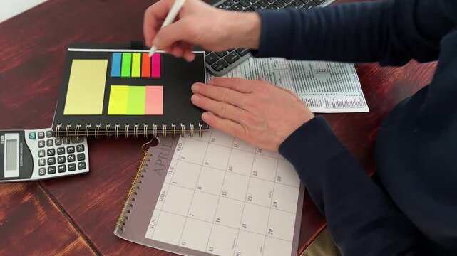 April 15, 2025, U.S. tax day. Person writing and annotating with a pencil, 1040 tax form. Desk with calendar and computer.