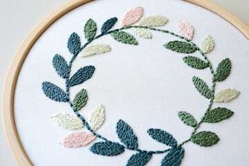 A wreath of leaves, embroidered with satin stitch on linen