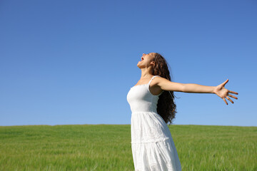 Happy woman screaming outstretching arms in green field