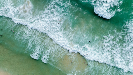 sea waves hitting the beach, tourists play in the sea and sunbathing on the sand beach at surin...