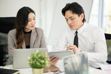 A male employee is presenting a business plan to a female executive in a conference room.