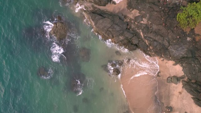 A stunning top aerial drone view of Cola Beach in Goa, India, with golden sands, calm waves, and rugged rocky coastline 4K