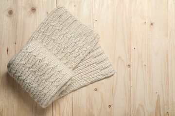 Knitted scarf on wooden table, top view. Space for text