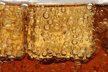 Refreshing soda water with ice cubes as background, closeup