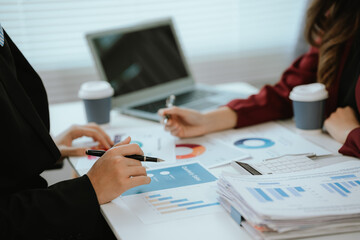 Close up of businessman and woman working in modern office, analyzing financial data, charts and investment reports on laptop and documents.