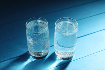 Refreshing soda water in glasses on light blue wooden table, closeup