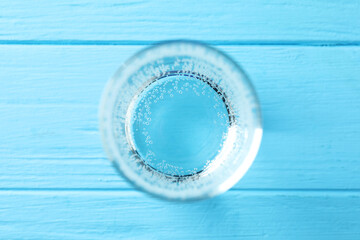 Refreshing soda water in glass on light blue wooden table, top view
