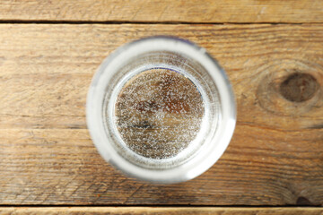 Refreshing soda water in glass on wooden table, top view